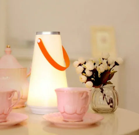 White rechargeable LED bedside night light with adjustable warm glow on wooden table