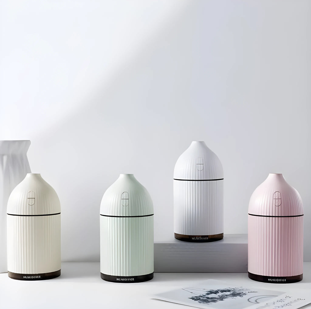 White ultrasonic aromatherapy diffuser and humidifier with LED light on a wooden surface.