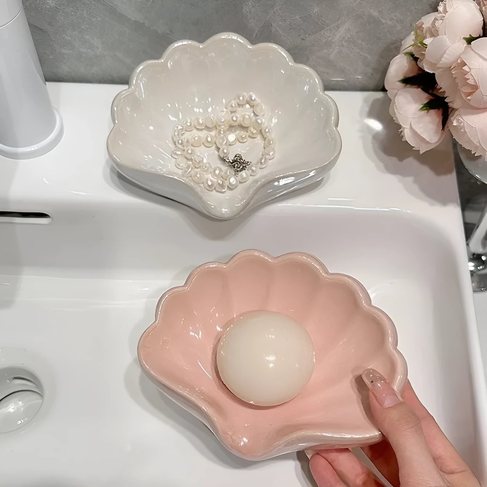 White or pink shell-shaped plastic soap dish for bathroom countertop.