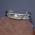 Custom engraved name bangle in stainless steel, silver colour finish, shown on a flat surface
