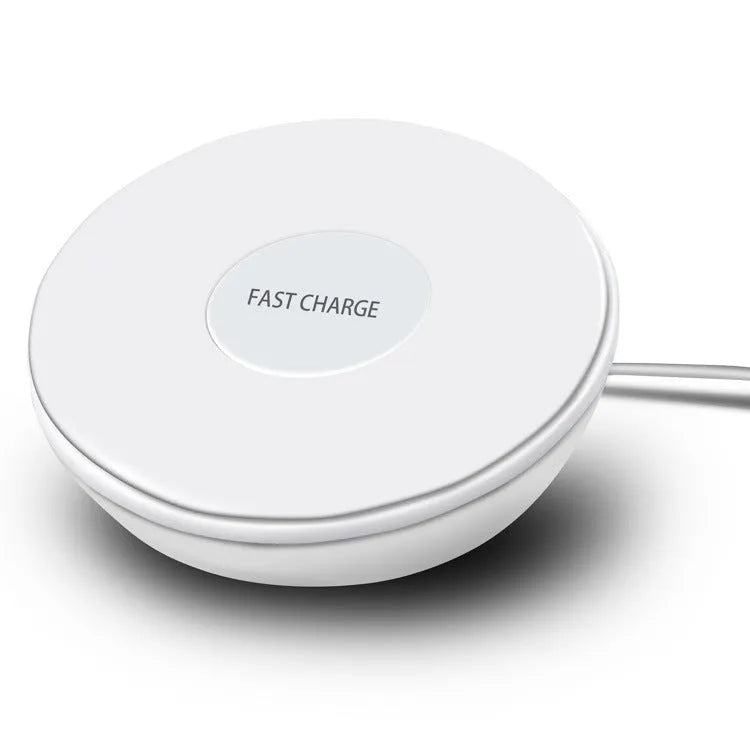 White Qi wireless charger with digital clock display on a desk next to a mobile phone.