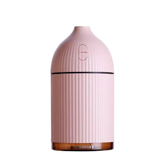 White ultrasonic aromatherapy diffuser and humidifier with LED light on a wooden surface.