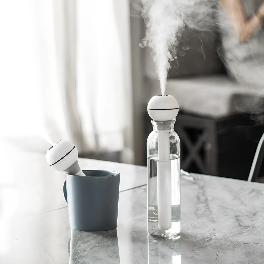 Columnar pink and white Magic Wand personal USB humidifier with water tank on a desk.