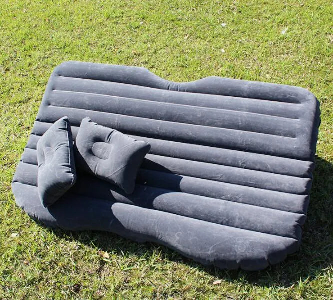 Inflatable car bed with flocked surface and two pillows, shown folded next to its storage bag.