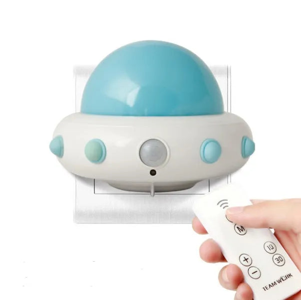 Blue UFO-shaped bedside night light with remote control on a table.