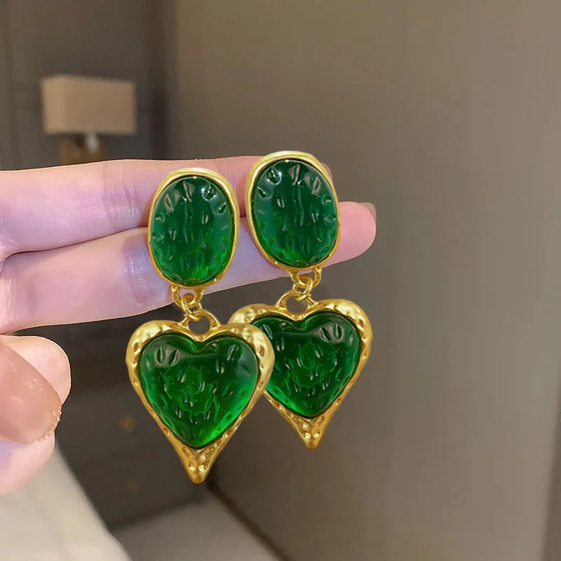 Oval-shaped love heart stud earrings with a pleated silver texture in purple, red, green, and yellow/white colours.