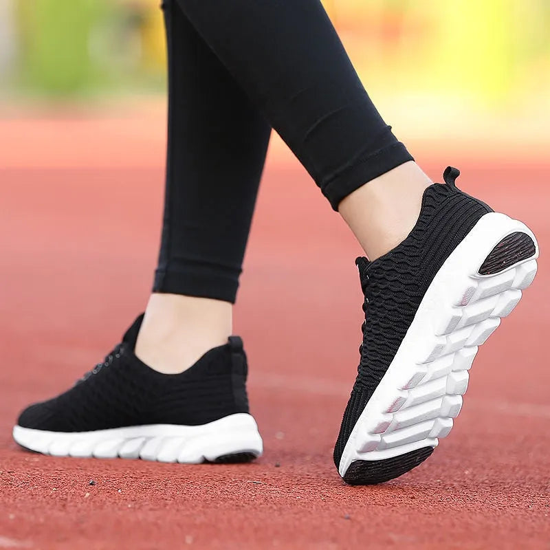 Women's fly knit running shoes in black, pink, or white colours, showing the woven upper and durable outsole.