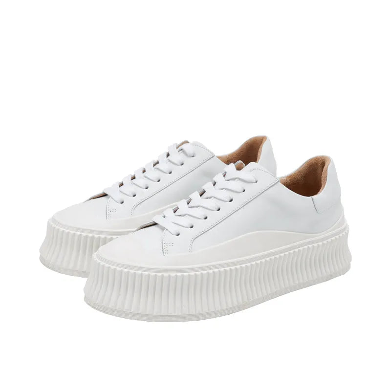 Women's black suede platform sneakers with back lacing, cross binding detail, and a thick sole on a white background.