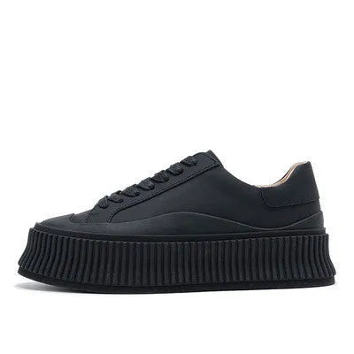 Women's black suede platform sneakers with back lacing, cross binding detail, and a thick sole on a white background.