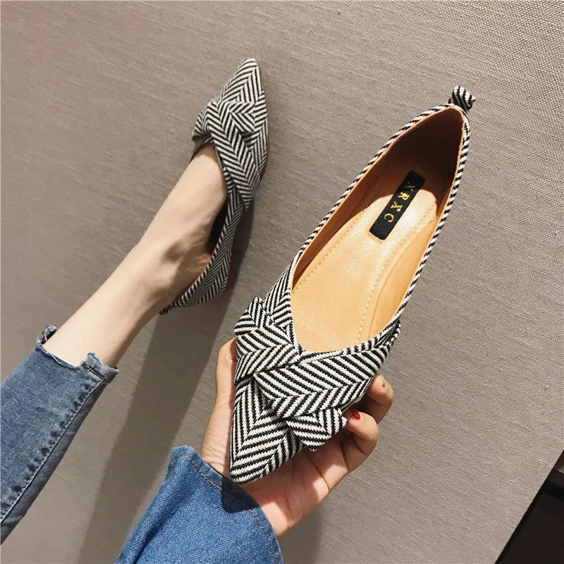 Women's red and black pointed-toe low-heel flats with a shallow mouth opening, shown from the side.