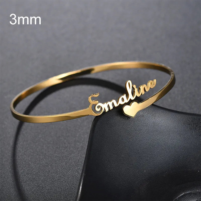 Custom engraved name bangle in stainless steel, silver colour finish, shown on a flat surface