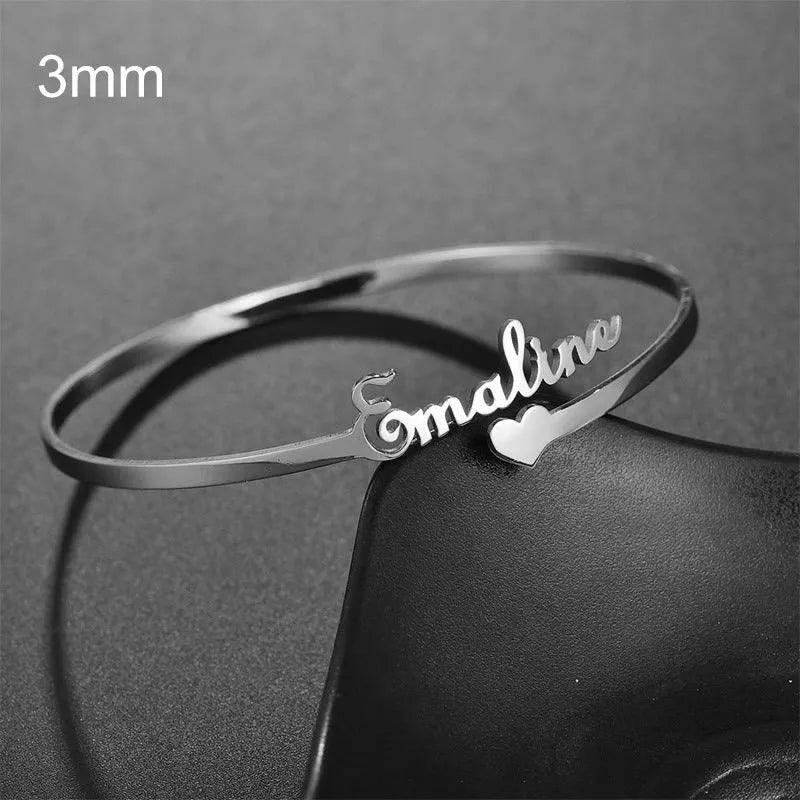 Custom engraved name bangle in stainless steel, silver colour finish, shown on a flat surface