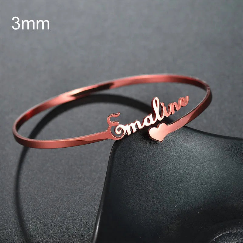 Custom engraved name bangle in stainless steel, silver colour finish, shown on a flat surface