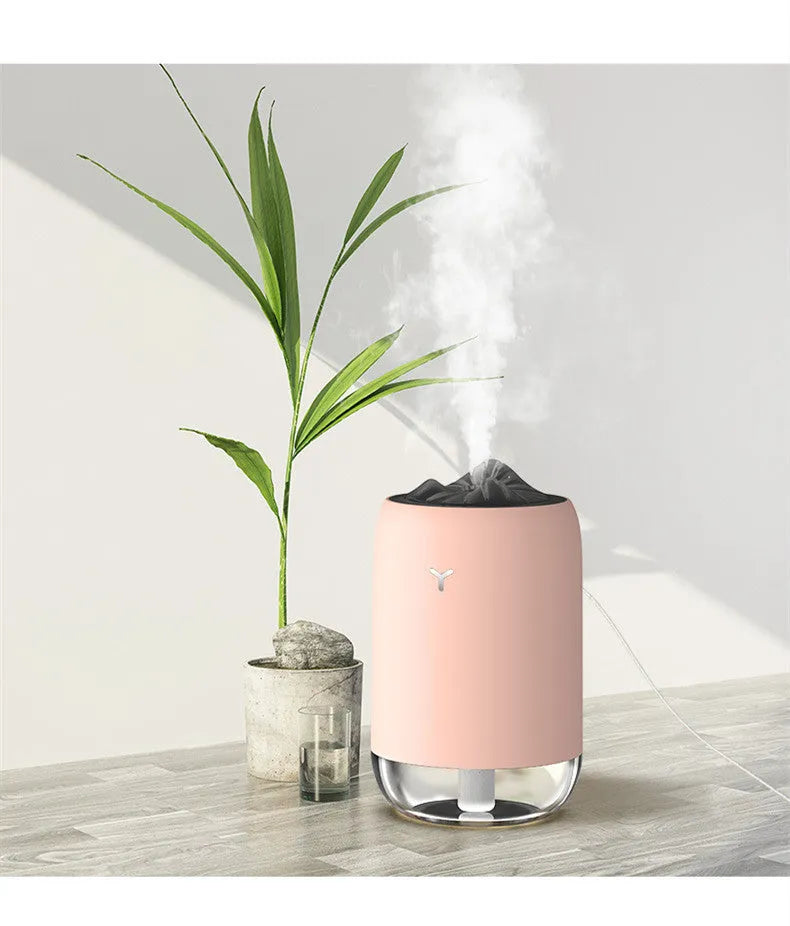 Magic Flame columnar humidifier in light blue on a wooden desk, showing USB cable and single mist outlet.
