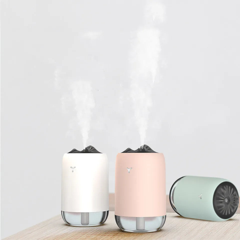 Magic Flame columnar humidifier in light blue on a wooden desk, showing USB cable and single mist outlet.