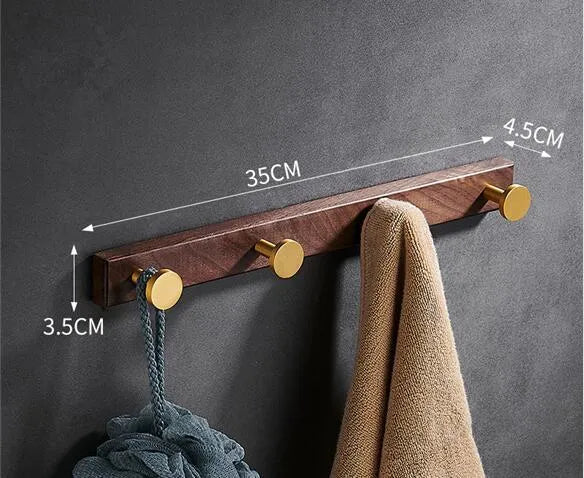 Black walnut bathroom clothes hook row with brass-finished aluminium hooks in perforated mounting design