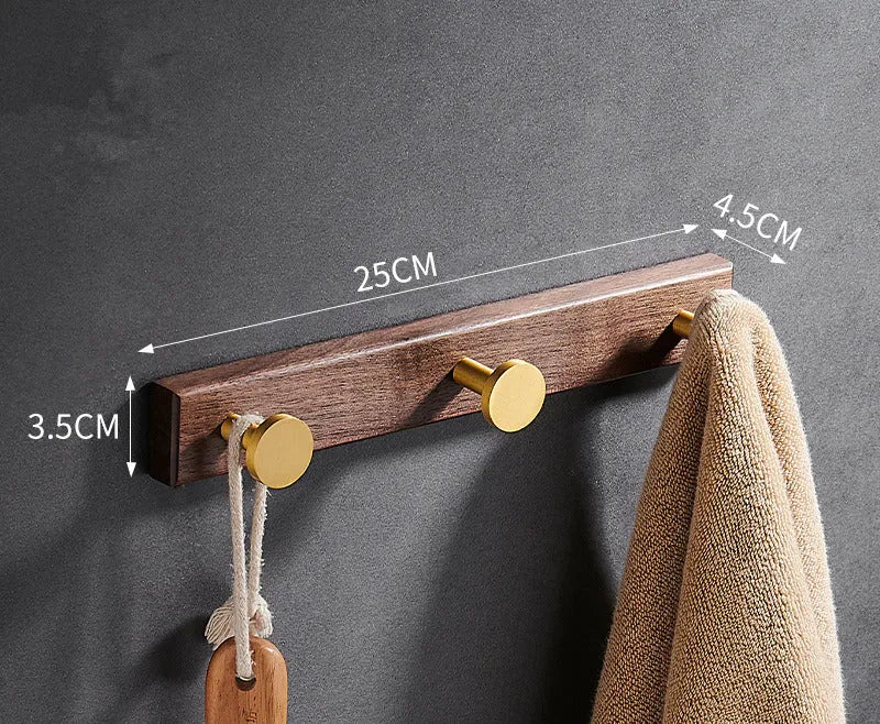 Black walnut bathroom clothes hook row with brass-finished aluminium hooks in perforated mounting design