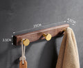 Black walnut bathroom clothes hook row with brass-finished aluminium hooks in perforated mounting design