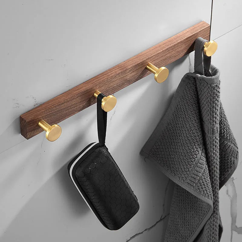 Black walnut bathroom clothes hook row with brass-finished aluminium hooks in perforated mounting design