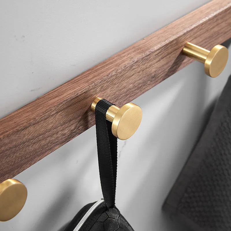 Black walnut bathroom clothes hook row with brass-finished aluminium hooks in perforated mounting design
