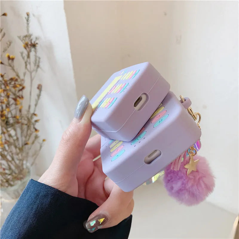 Purple silicone AirPods case with clamshell design and fur ball pendant