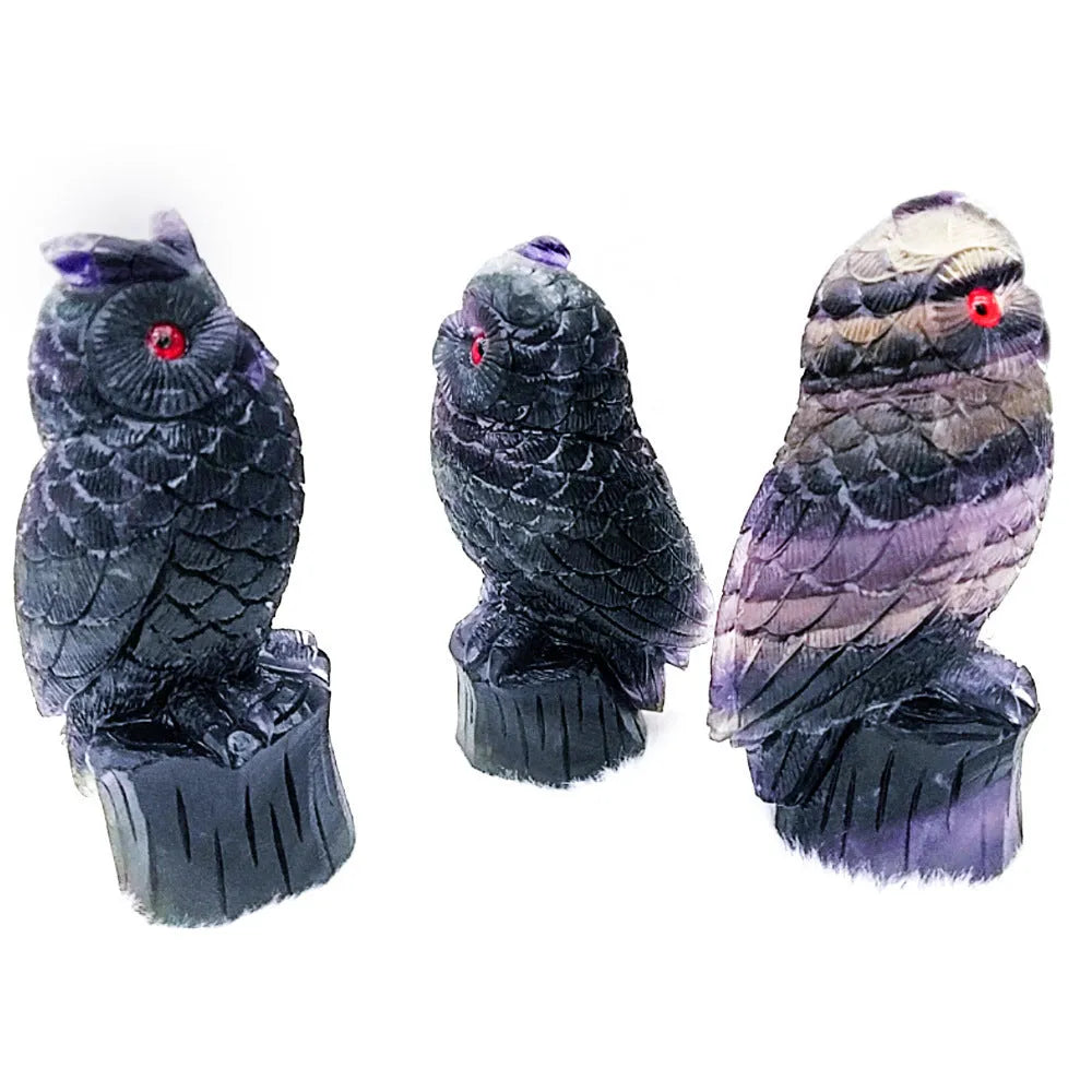 Hand carved purple fluorite stone owl ornament on a wooden surface.