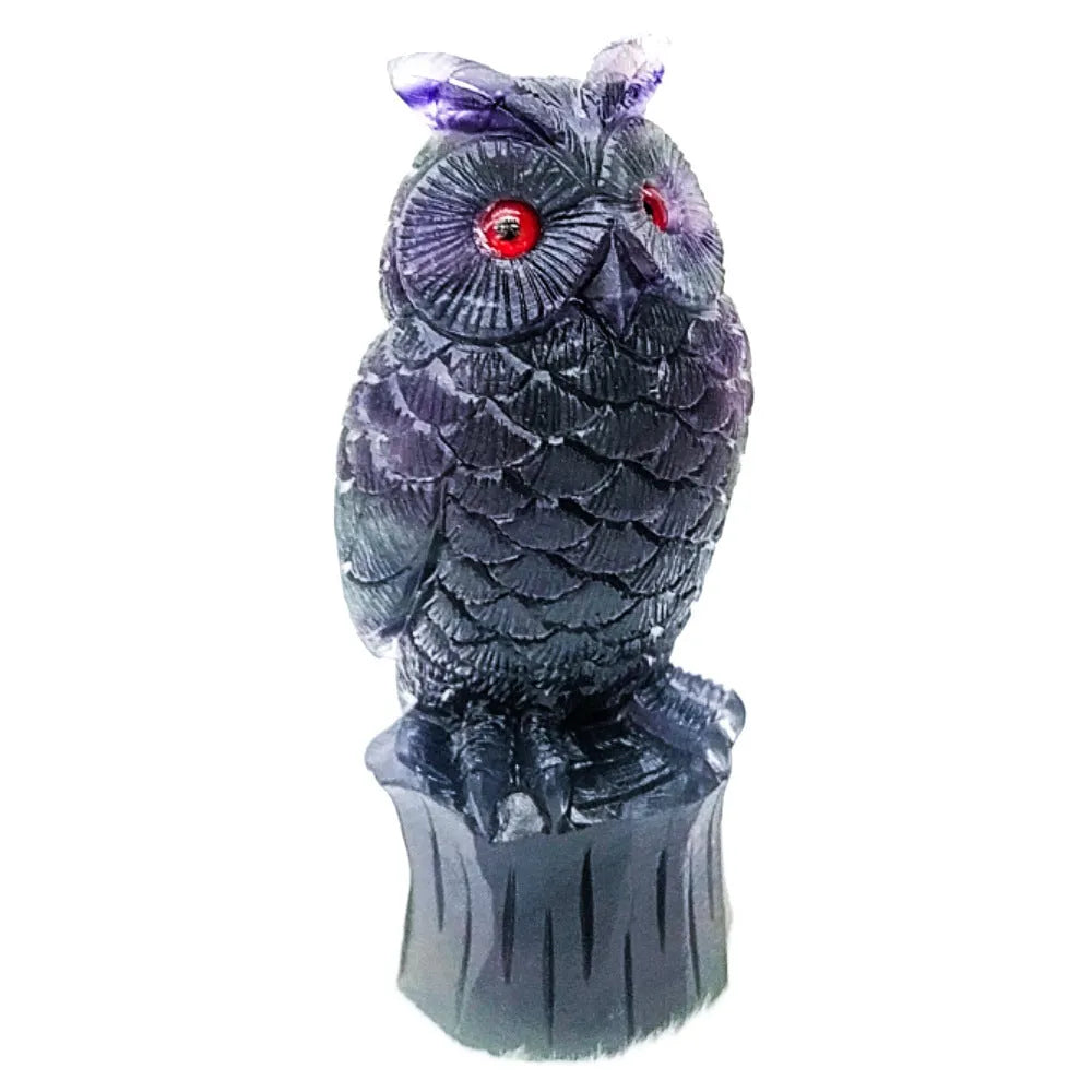 Hand carved purple fluorite stone owl ornament on a wooden surface.