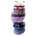 Hand carved purple fluorite stone owl ornament on a wooden surface.