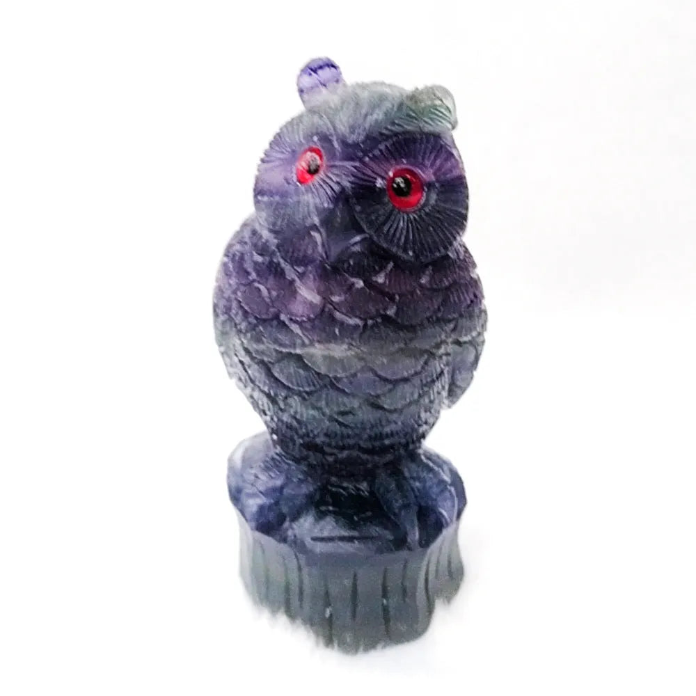 Hand carved purple fluorite stone owl ornament on a wooden surface.