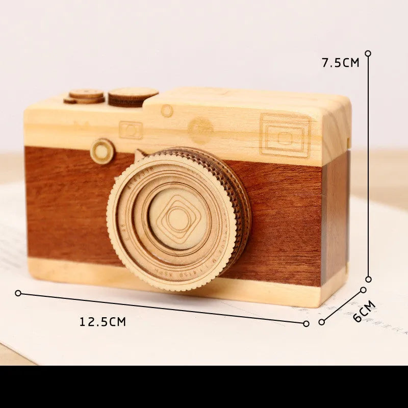 Small wooden music box with rotating camera decoration on pine wood base.