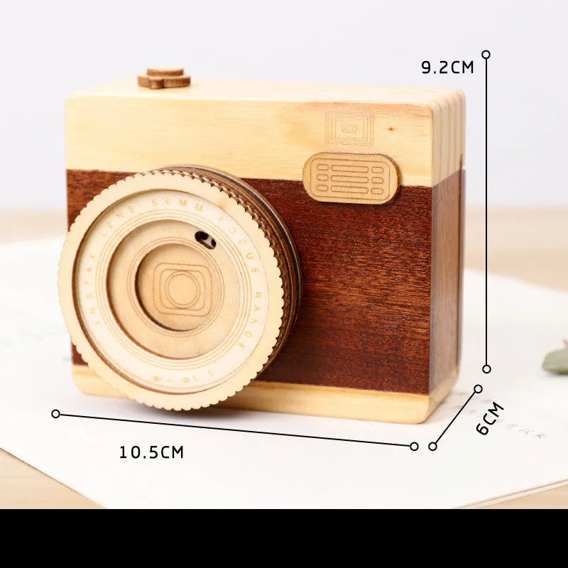 Small wooden music box with rotating camera decoration on pine wood base.