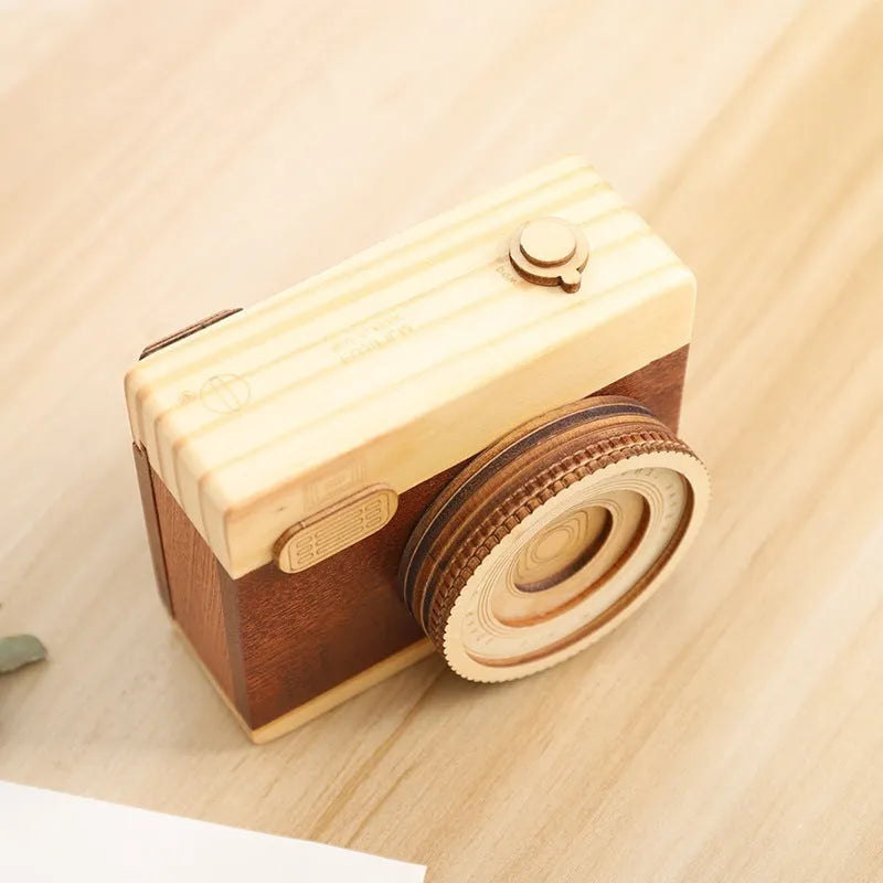 Small wooden music box with rotating camera decoration on pine wood base.