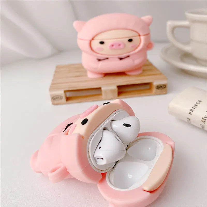 Pink silicone AirPods case with a cartoon pig design and a silver metal keyring hook attached.