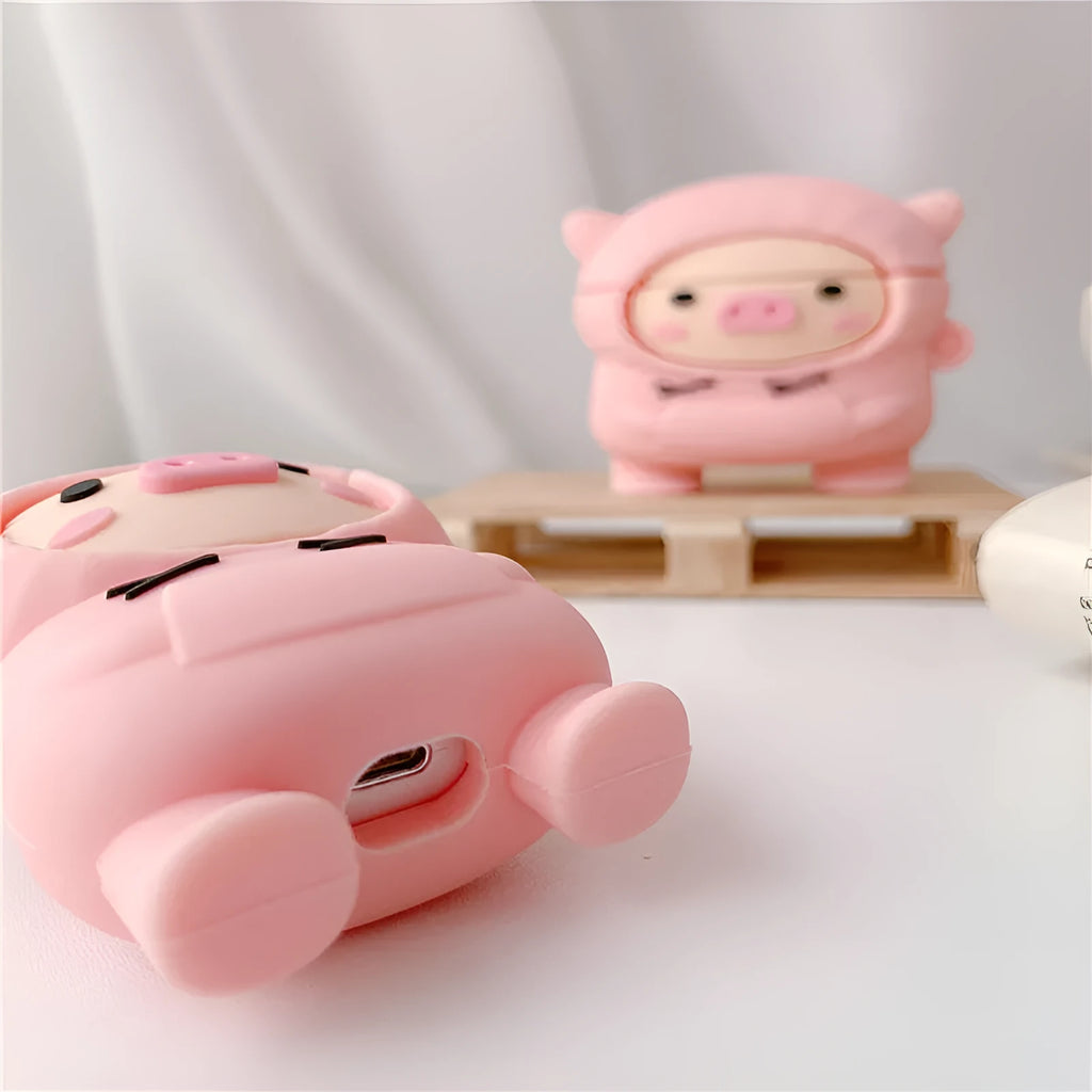 Pink silicone AirPods case with a cartoon pig design and a silver metal keyring hook attached.