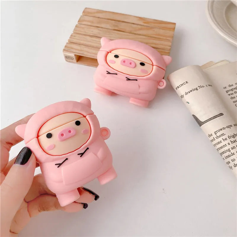 Pink silicone AirPods case with a cartoon pig design and a silver metal keyring hook attached.