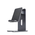 Dark grey alloy lazy bracket phone holder clamped to a desk edge, holding a mobile phone.