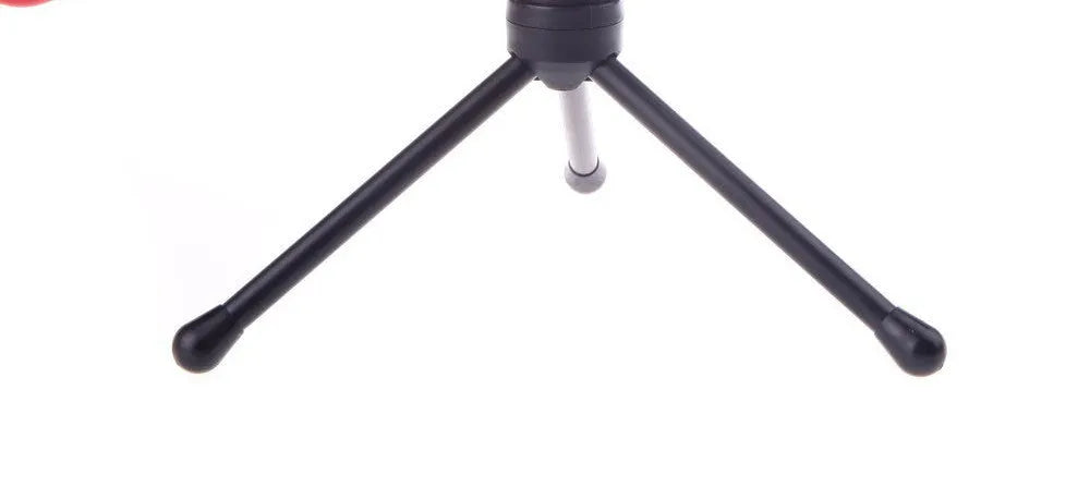 Black wired PC microphone with a metal clip holder on a desk next to a computer.