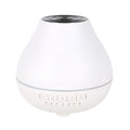 Round white Bluetooth humidifier and essential oil diffuser with night light on wooden surface