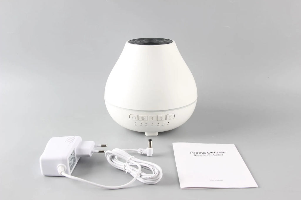 Round white Bluetooth humidifier and essential oil diffuser with night light on wooden surface