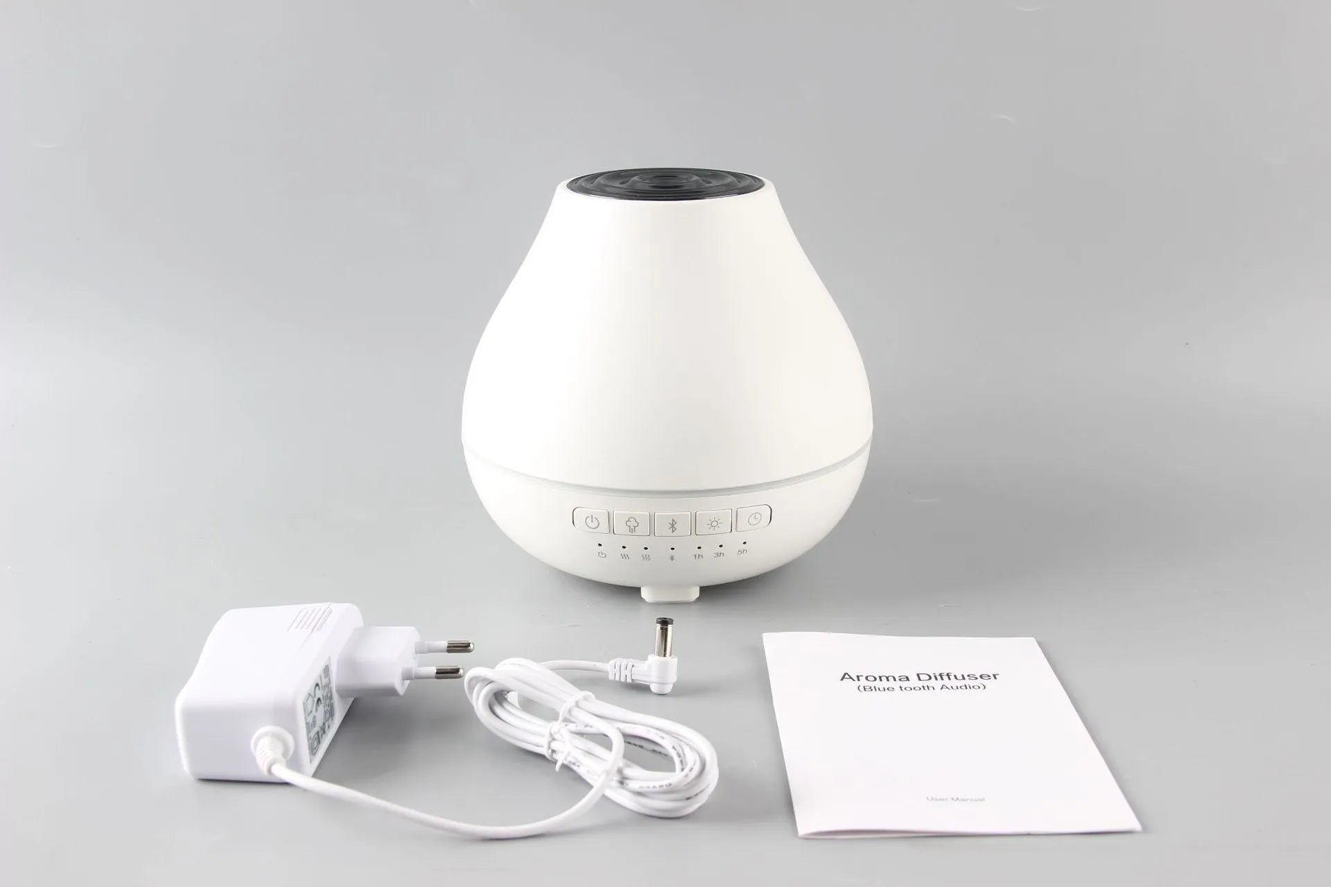 Round white Bluetooth humidifier and essential oil diffuser with night light on wooden surface