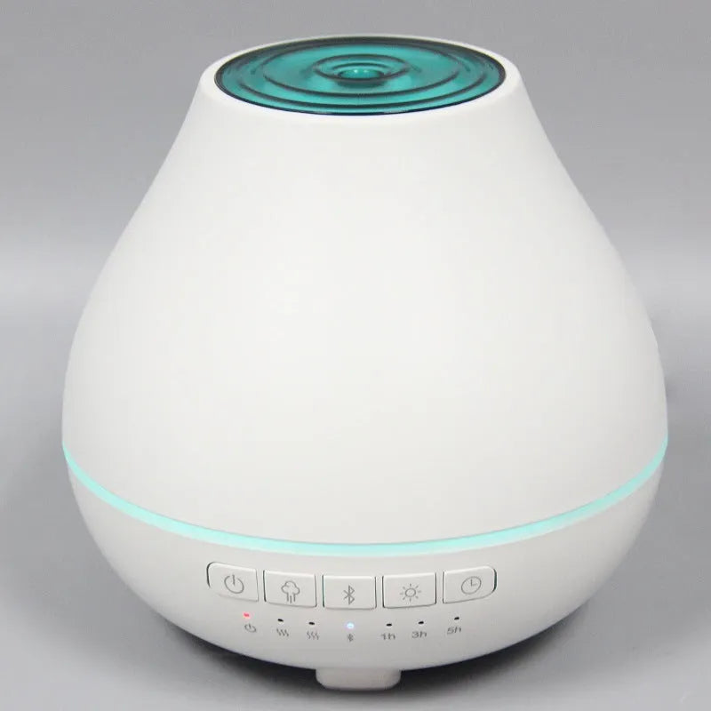 Round white Bluetooth humidifier and essential oil diffuser with night light on wooden surface
