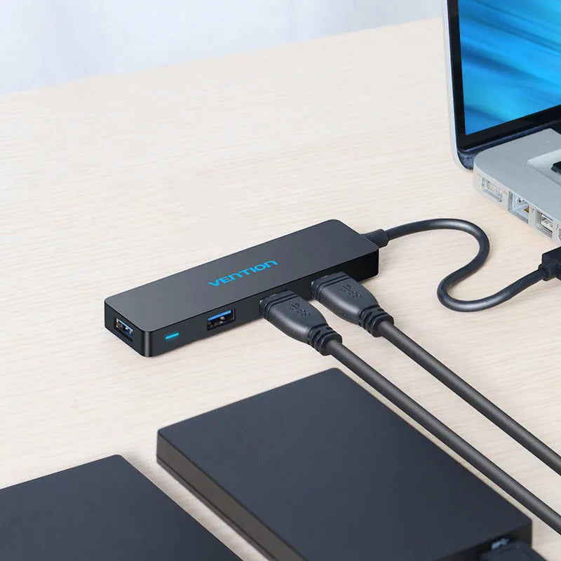 Black four-port USB 3.0 hub with a short integrated cable on a desk