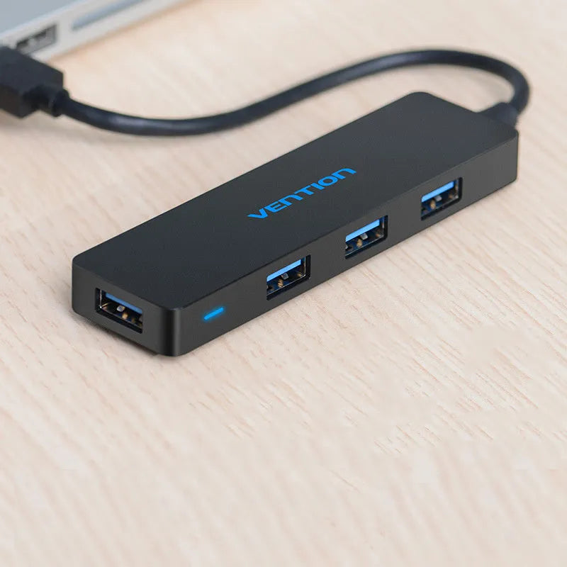 Black four-port USB 3.0 hub with a short integrated cable on a desk