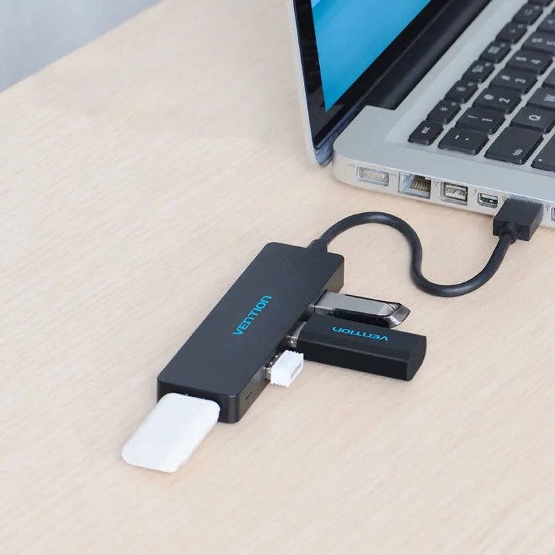 Black four-port USB 3.0 hub with a short integrated cable on a desk
