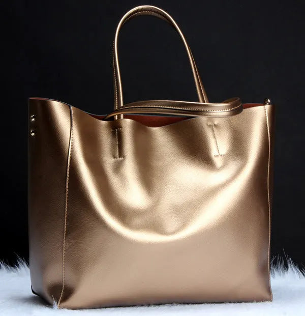 Women's black cowhide leather shoulder bag with a shoulder strap, shown next to a bronze coloured version.