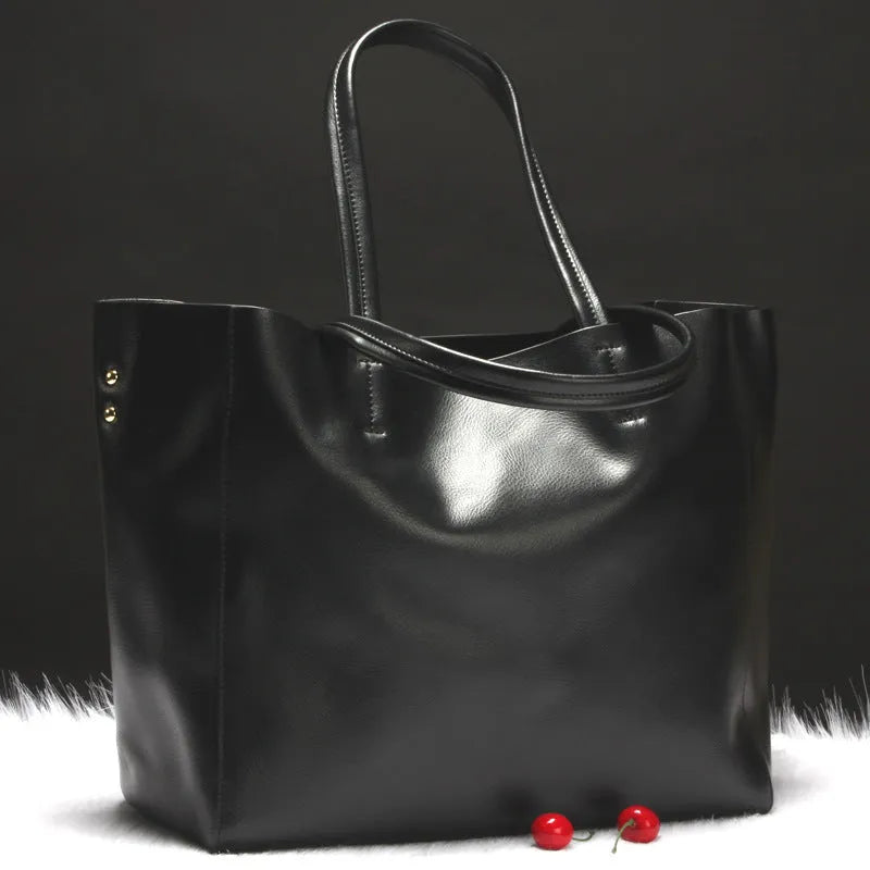 Women's black cowhide leather shoulder bag with a shoulder strap, shown next to a bronze coloured version.