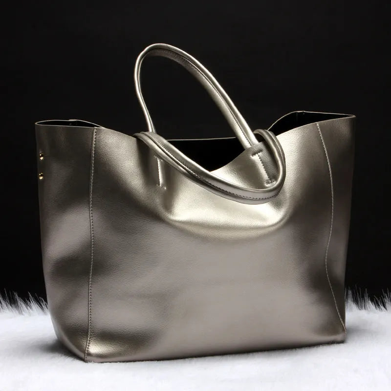 Women's black cowhide leather shoulder bag with a shoulder strap, shown next to a bronze coloured version.