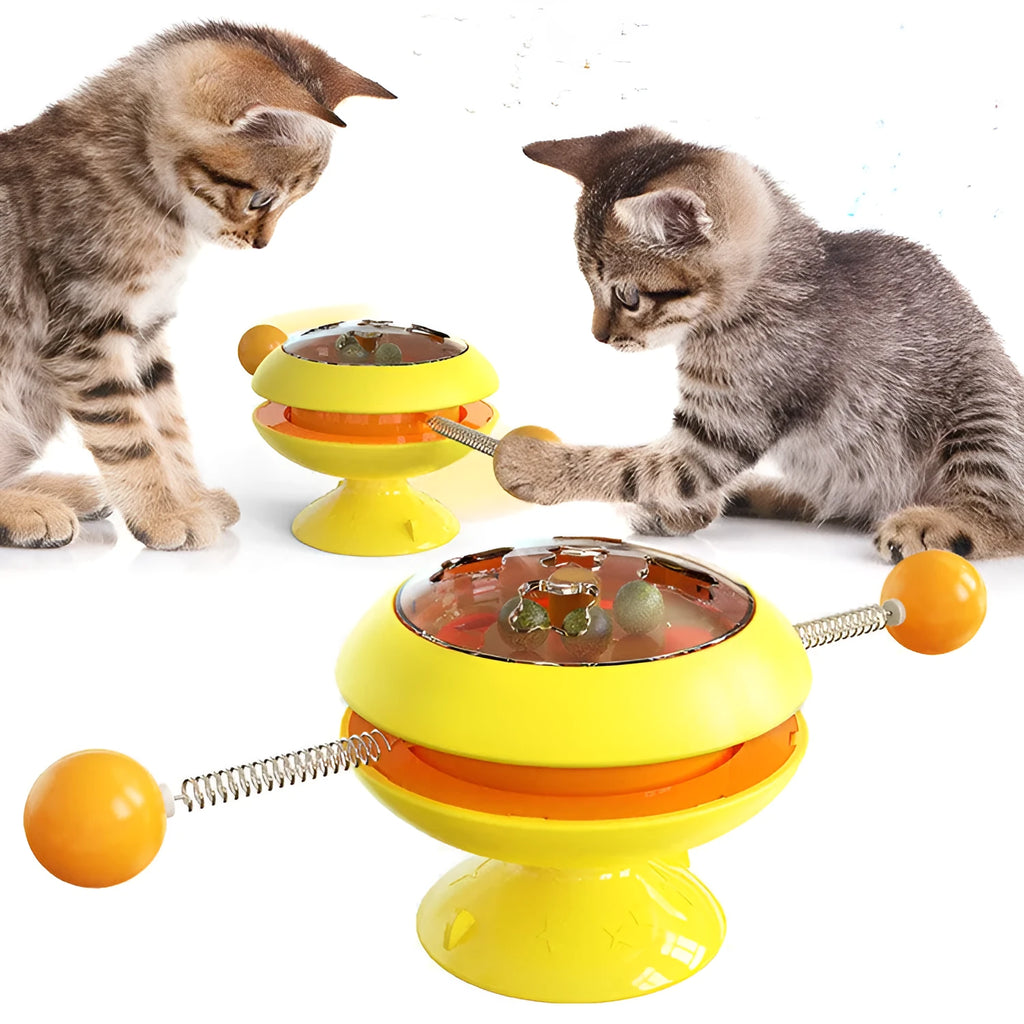 Rotatable cat toy with colourful turntable, stick elements, and transparent top holding catnip balls on a suction cup base.