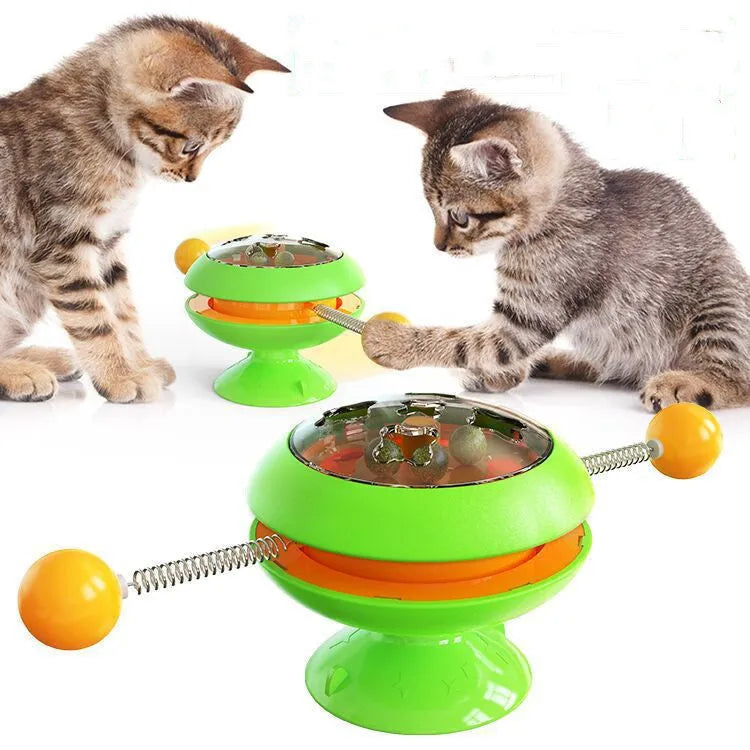Rotatable cat toy with colourful turntable, stick elements, and transparent top holding catnip balls on a suction cup base.