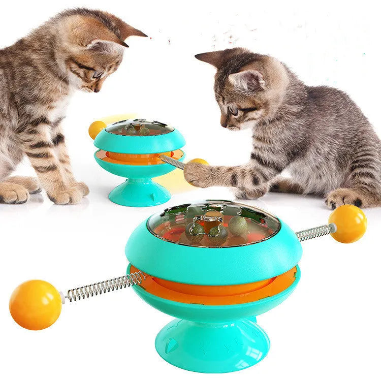 Rotatable cat toy with colourful turntable, stick elements, and transparent top holding catnip balls on a suction cup base.